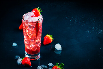 Red alcoholic cocktail drink with vodka, grapefruit juice, strawberries, sugar and hot chili pepper. Highball glass on dark blue background