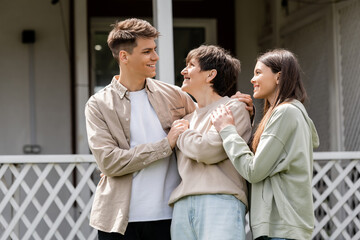 happy parents day, cheerful son and teenage daughter hugging cheerful middle aged mother on backyard of family house, celebration, bonding, candid, modern parenting, moments to remember