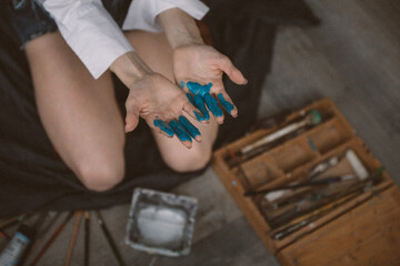 An artist in a moment of inspiration paints a picture. Close-up hands in paint.
