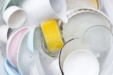 Dishes and bowls in water and bubbles of dishwashing liquid. Kitchen work