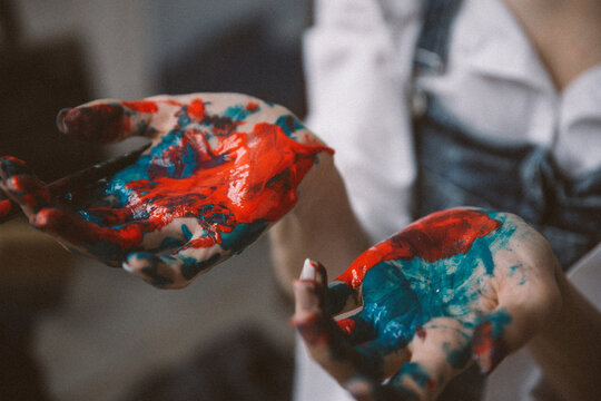 An artist in a moment of inspiration paints a picture. Close-up hands in paint.