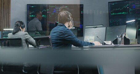 Diverse stock traders monitor real-time stocks data on computers, work in broker agency office....