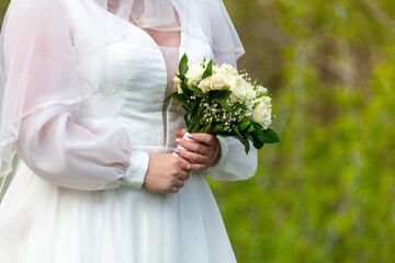 Wedding bouquet of white roses in the hands of the brideWedding bouquet of white roses in the hands of the bride