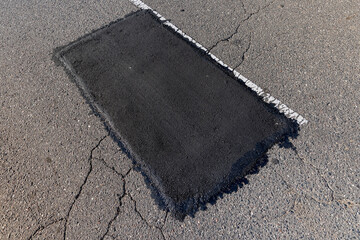 The repaired part of an asphalt road with patches