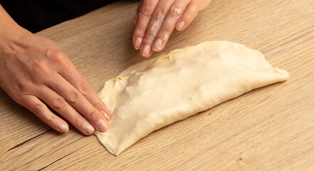 Female hands kneading dough on a wooden table. Close-up