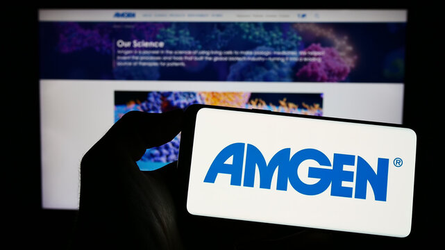 Stuttgart, Germany - 06-17-2023: Person holding cellphone with logo of US biopharmaceutical company Amgen Inc. on screen in front of business webpage. Focus on phone display.