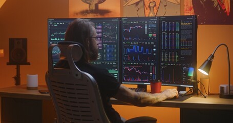 Male stock trader analyzes real-time stocks, exchange market charts on multi-monitor computer workstation, eats french fries. Man works in investment at home office at night. Cryptocurrency trading.