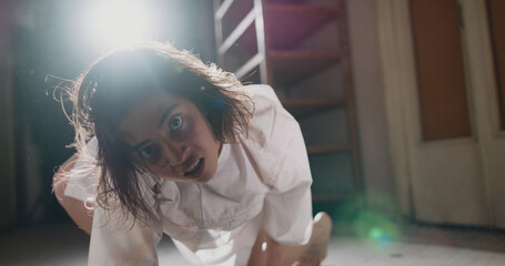Scary female psychopath crawling in corridor of cursed house with unnatural moves. Exorcist girl...