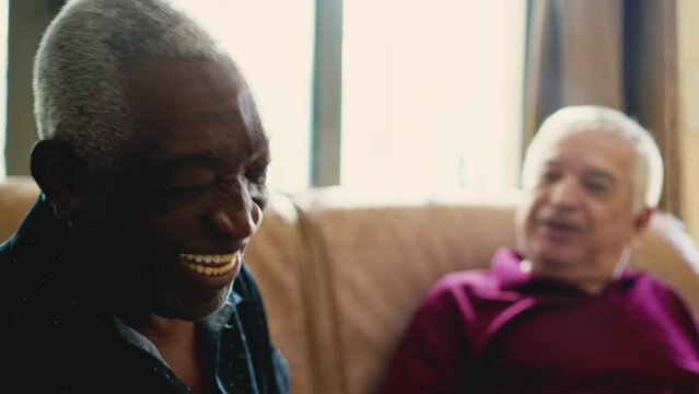 A charismatic black Senior man laughing and smiling at friend's joke. Candid senior people relationship in laughter