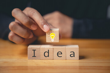 Expert consulting and creative solution concept. Hand holding wooden block with light bulb icon. Development of new ideas and innovation strategy. Business success through creative imagination.