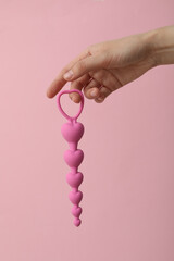Pink anal chain in hand on pink background