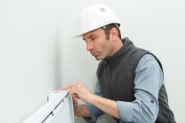man installing radiator against wall