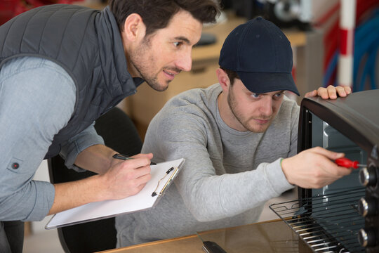 apprentice and man work on an oven