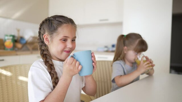 children drinking juice. happy family a healthy eating kid dream concept. daughter son drinking yellow juice from a glass cup in kitchen indoor. child drinking fruit juice. Young team drinking juice
