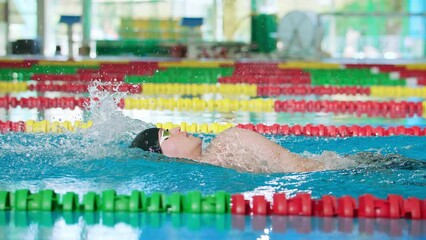 Slow motion of professional male athlete swimming backstroke in the pool, arms movement, slow motion tracking shot. Competitive swimming drills concept.