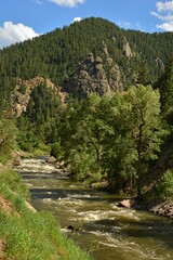 Fototapeta na wymiar rocks and rapids on in the south platte river on a sunny summer day in the granite foothills of waterton canyon, littleton, colorado