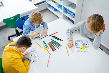 Children drawing paint with colorful pencils coloring book in educational class at school. Art...