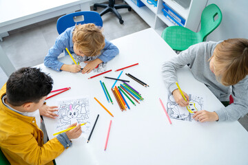 Children drawing paint with colorful pencils coloring book in educational class at school. Art...