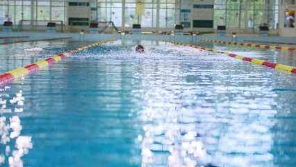 Front view of a female swimmer swimming butterfly style, a stroke performing in a competitive swimming, slow motion shot. Success, power, and strength concept.
