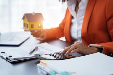 home loan officer uses a calculator with a house plan.