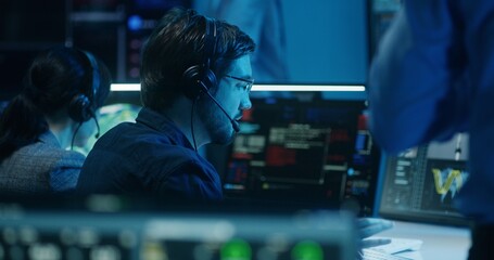 Diverse flight control operators in headsets monitor space mission on computers in mission control center. Team clap hands after successful space rocket launch displayed on big digital screens.