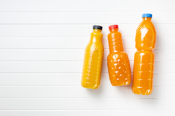 A plastic bottle of fruit juice. Orange  juice on white table. Top view.