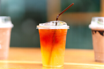 Lemon tea in a plastic glass with straws on the table.