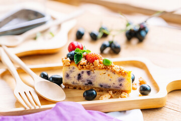 Sliced berry cheesecake served on a wooden plate.