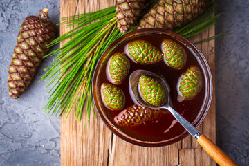 Young pine cones jam in glass bowl on wooden board. Delicious jam with the little pine cones.