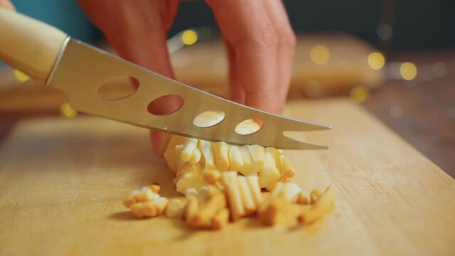 Cuts cheese in close-up with a cheese knife. Selective focus