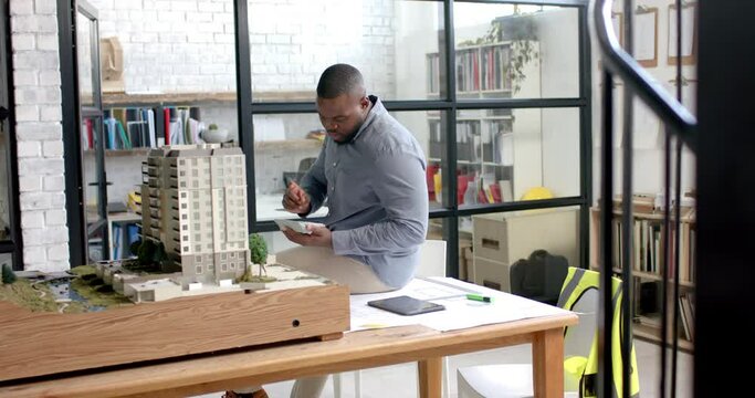 African american male architect building architectural model at office, slow motion