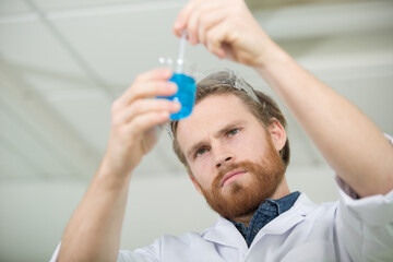 male scientist stirring liquid in a flask