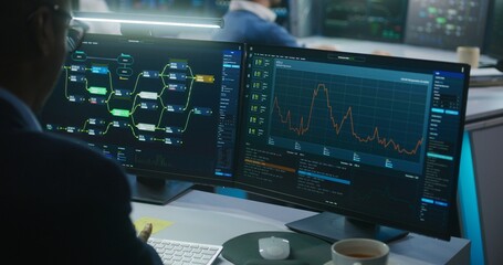 Multiracial team of IT software engineers work in monitoring office. Data server, blockchain network and live analysis charts displayed on computers and big digital screens. Concept of cyber security.