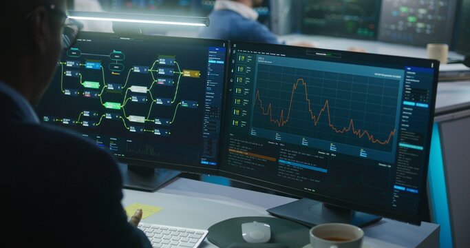 Multiracial team of IT software engineers work in monitoring office. Data server, blockchain network and live analysis charts displayed on computers and big digital screens. Concept of cyber security.