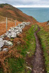 Fototapeta na wymiar Autumn or fall path with remains of dry stone wall, and sea in distance.