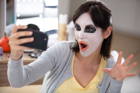 crazy woman in bright halloween make up taking a selfie