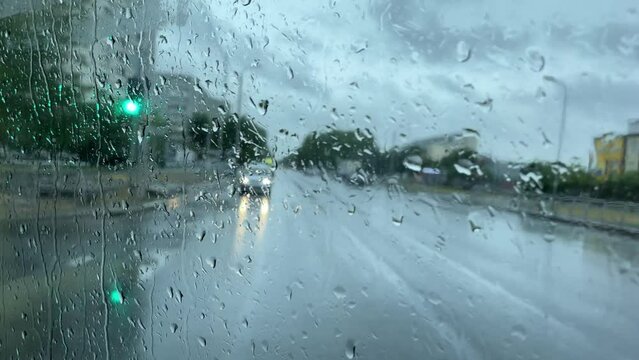 Close-up of the west glass window of a motor vehicle, with raindrops falling in background.