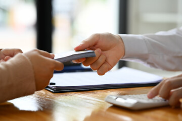 Fototapeta premium Closeup view man giving cash money to female customer. Currency exchange, loan approved finance and banking concept