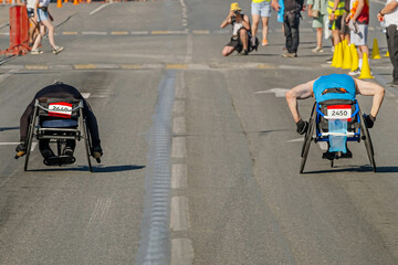 two wheelchair racers they go together at marathon race, city summer athletics sports games