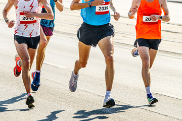 four athlete runners running marathon race in city road, numbers on shirts, summer sports games