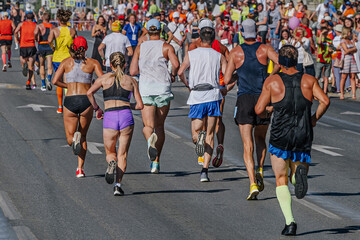 rear view group runners athletes women and men running city marathon, roadside fans watch athletes