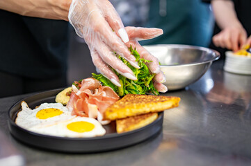 woman chef hand cooking fried eggs with ham, salad and hummus