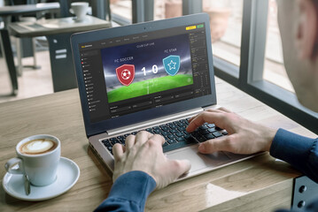 Man follows the soccer match result on a laptop. Concept of online betting and live score