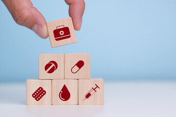 The hand holding a wooden cube with icons - tablets, capsule, Band-Aid, tests, syringe. Close up.