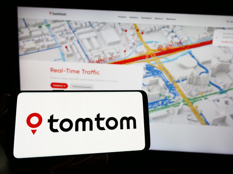Stuttgart, Germany - 06-17-2023: Person holding mobile phone with logo of Dutch location technology company TomTom N.V. on screen in front of web page. Focus on phone display.