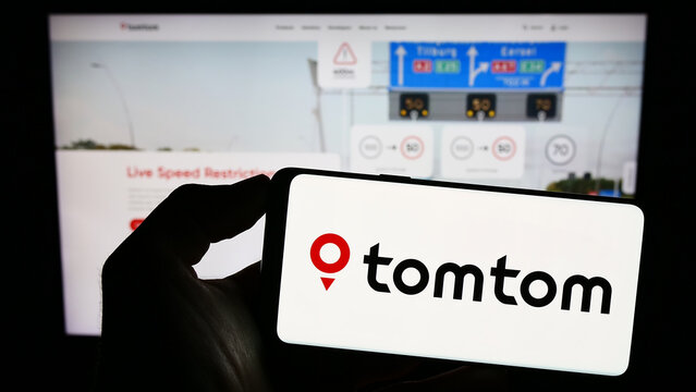 Stuttgart, Germany - 06-17-2023: Person holding cellphone with logo of Dutch location technology company TomTom NV on screen in front of business webpage. Focus on phone display.