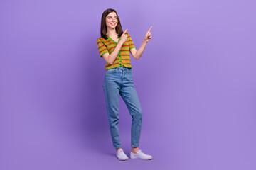 Full length photo of cheerful adorable lovely lady wear trendy clothes hands demonstrate empty space isolated on purple color background