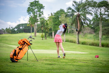 Fototapeta premium Professional woman golfer teeing to hole in player tournament competition at golf course for winner with green golf background.