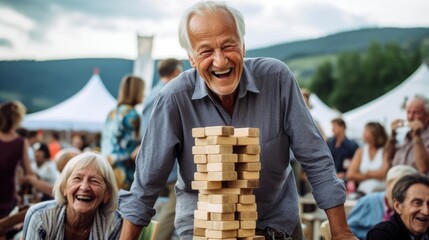 An older man with a wide grin, playing an oversized game of Jenga at an outdoor gathering.