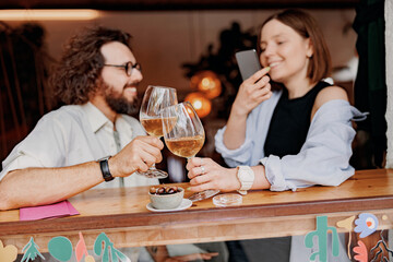 Couple during date drinking wine and making photo while sitting in bar